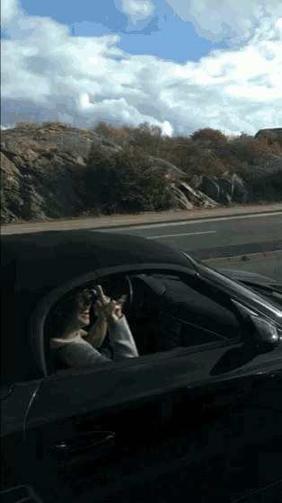 a person driving a car with a blue sky in the background