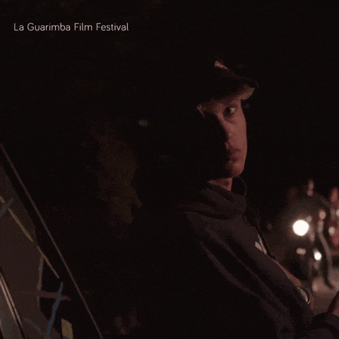 a man wearing a black hat is standing in the dark with the words la guarimba film festival behind him