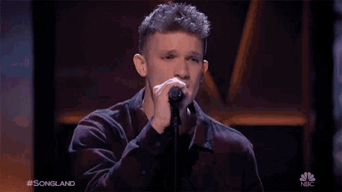a man singing into a microphone with the words #songland on the bottom