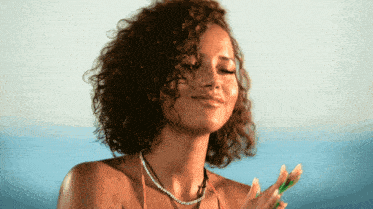 a woman with curly hair is wearing a necklace and a bikini top