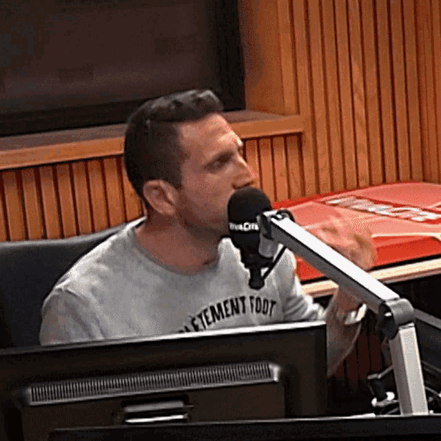 a man wearing a t-shirt that says " etement toot " is speaking into a microphone