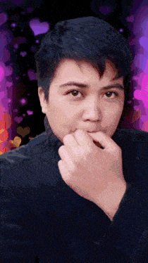 a man covering his mouth with his hand in front of a pink background