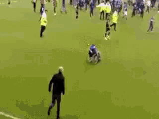 a man is pushing another man in a wheelchair on a soccer field