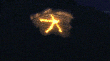 a person with glasses is looking at a large chinese symbol on a rock
