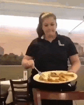 a woman is sitting at a table with a plate of food on it .