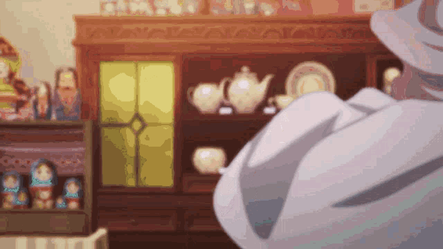 a man in a white coat stands in front of a cabinet full of plates and a teapot