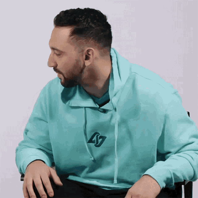 a man with a beard wears a light blue sweatshirt with the letter s on it