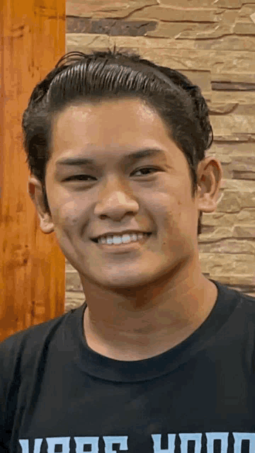 a young man wearing a t-shirt that says your hood smiles for the camera