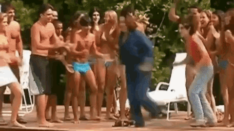 a group of people in bikinis are dancing on a stage in front of a pool .