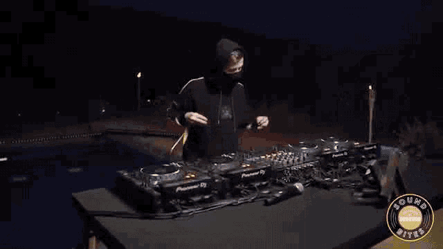 a man in a yellow jacket is playing music in front of a pioneer dj mixer