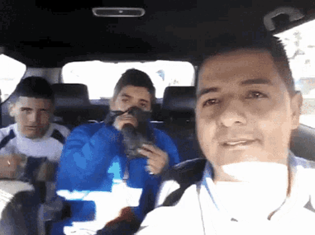 three men are sitting in the back seat of a car and one is holding a pair of shoes