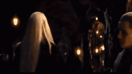a woman with long blonde hair is standing in a dark room .