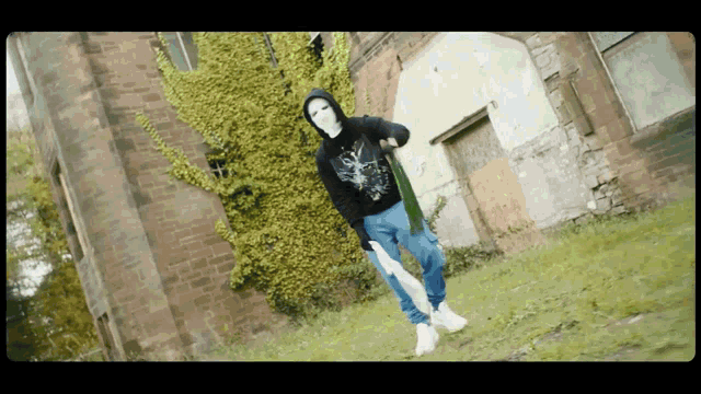 a man wearing a mask is holding a knife in front of a brick building
