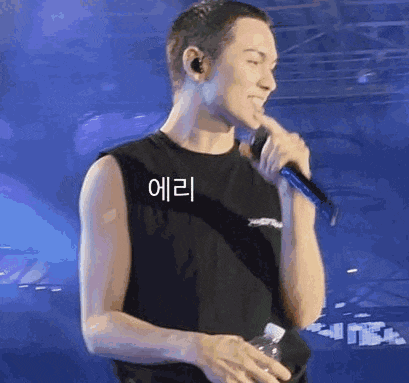 a man is holding a microphone in his hand and smiling while standing on a stage .