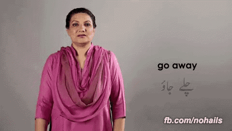 a woman in a pink dress is standing in front of a wall with the word go away written on it .