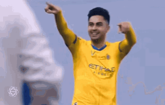 a soccer player in a yellow jersey is giving a thumbs up and smiling .