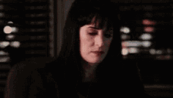 a woman is holding a gun in her hand in a dark room .