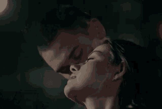 a man and a woman are kissing in the dark in a dark room .