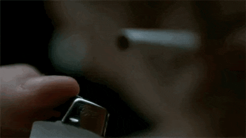 a person is lighting a cigarette with a lighter in the dark .