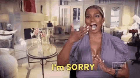 a woman in a purple dress is saying i 'm sorry in a living room with her mouth open .
