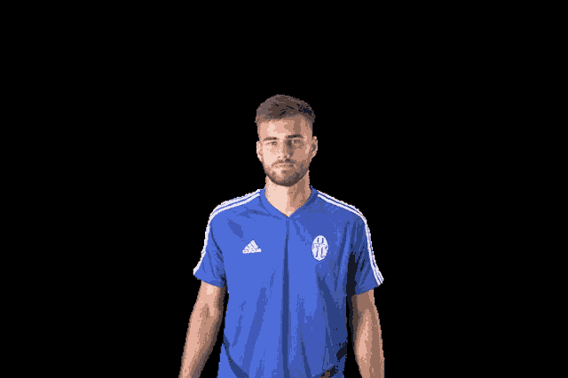 a man wearing a blue adidas shirt holds his fist up in the air