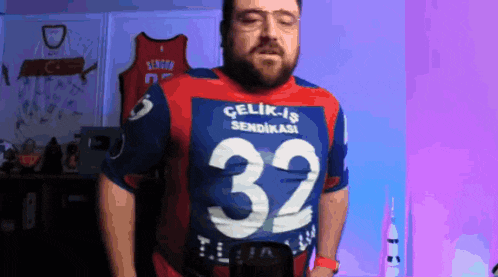a man with a beard wears a red and blue shirt with the number 32 on it