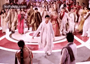 a man is dancing in front of a crowd of people in a room .