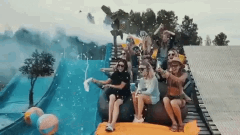 a group of people are sitting on a roller coaster at a water park .