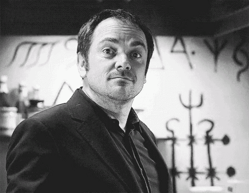 a man in a suit is standing in front of a wall with the letters a and y written on it