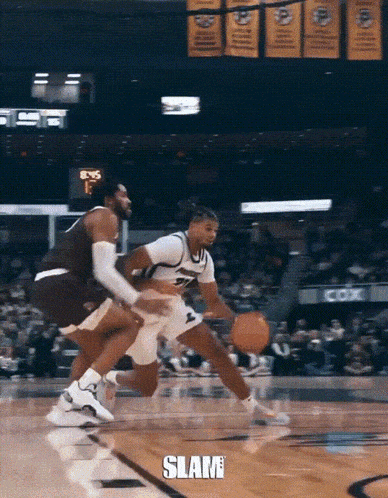 a basketball player dribbles the ball while another player tries to stop him