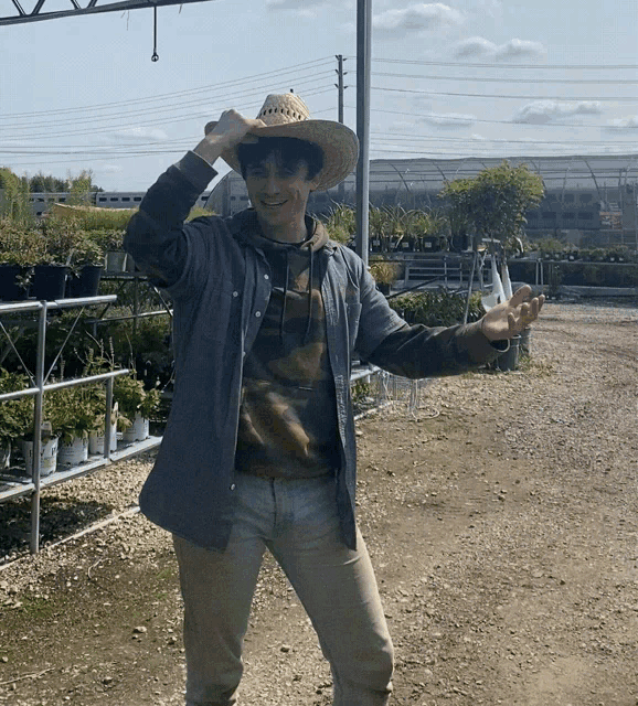 a man wearing a cowboy hat is standing in front of a display of potted plants