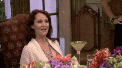 a woman is sitting at a table with a martini glass .
