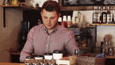 a man in a plaid shirt is behind a counter with a sign that says 8.5