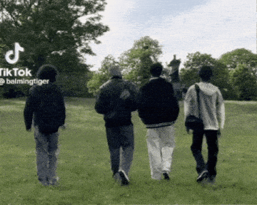 a group of people walking in a grassy field with a tiktok logo in the background
