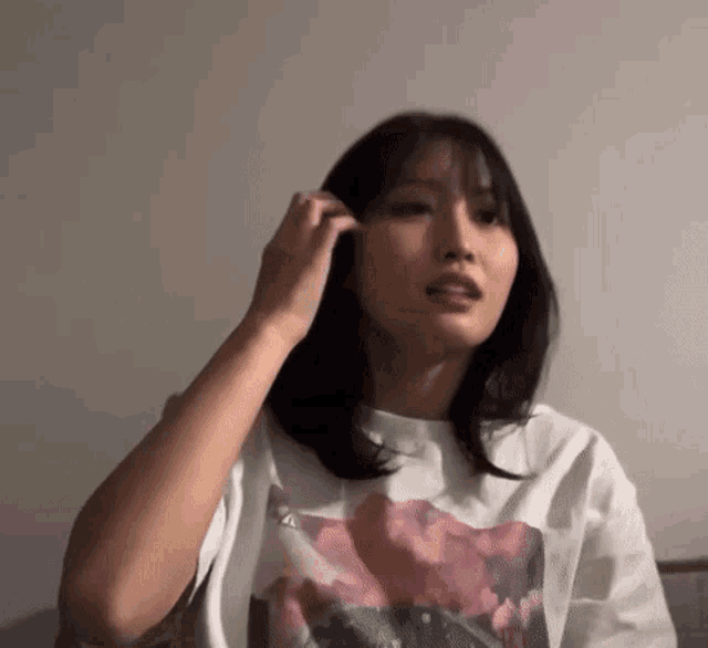 a woman wearing a white t-shirt is sitting on a couch and brushing her hair .