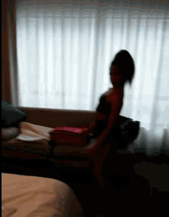 a blurred image of a woman sitting on a couch in front of a window