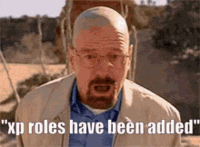 a bald man with a beard and glasses is standing in the desert .