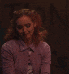 a woman in a purple cardigan is holding a glass of wine .
