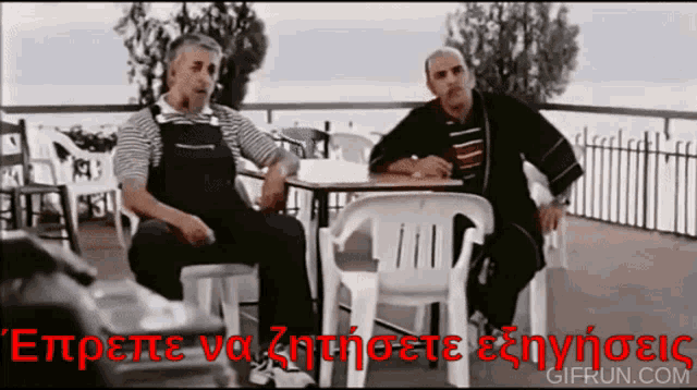 two men are sitting at a table with a sign that says ' gifrun.com '