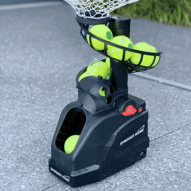 a black spinshot home tennis ball machine with tennis balls in it