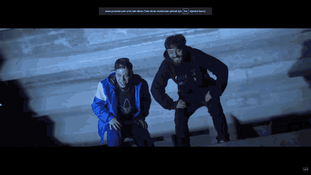 two men standing next to each other on a wall with a youtube logo on the bottom right