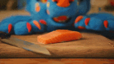 a blue furry costume is cutting a piece of salmon on a cutting board .