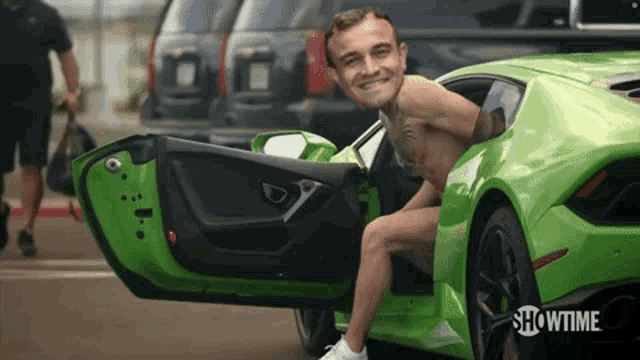 a shirtless man is getting out of a green sports car