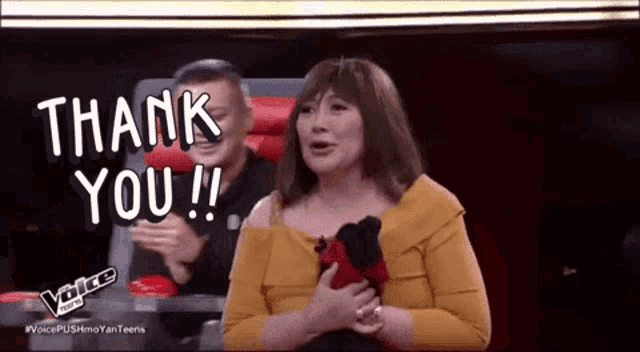 a woman in a yellow shirt is sitting in front of a screen that says thank you !