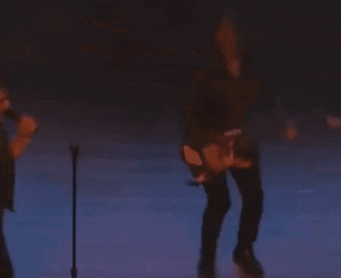 a blurry photo of a man playing a guitar on stage