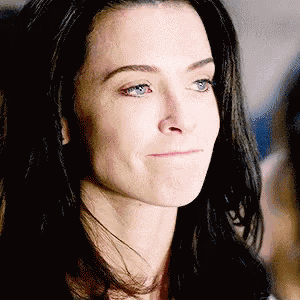 a woman with long black hair and blue eyes is smiling