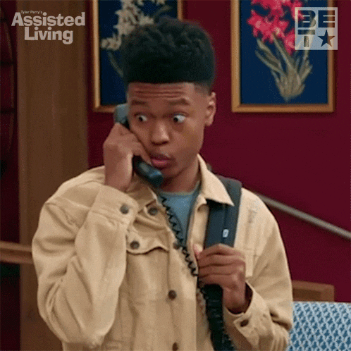 a young man is talking on a telephone and making a surprised face .