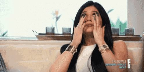 a woman is crying while sitting on a couch with her hands on her face .