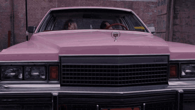 a pink cadillac is parked in front of a building