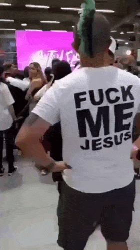 a man with a mohawk wearing a white shirt that says fuck me jesus
